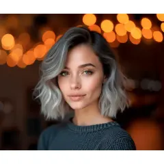 Mujer con pelo corto rubio platino ceniza, mirada cautivadora y luces cálidas de fondo.