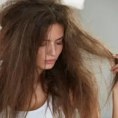 Mujer con pelo seco y enredado, buscando cómo hidratar el pelo para devolverle la vida y el brillo.