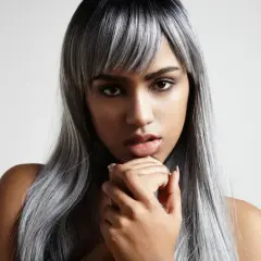 Mujer con cabello largo y liso, con mechas blancas que contrastan con su tono oscuro.