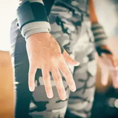 Manos con callos en los dedos, evidencia de entrenamiento duro. Muñequeras y pantalón de camuflaje completan la imagen.