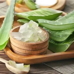 Gel de aloe vera en un cuenco de madera, junto a hojas cortadas. Ideal para el cuidado del aloe vera en el pelo.