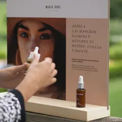 Manos sostienen un frasco de serum de vitamina C, ideal para combatir las manchas que la vitamina C mancha la piel con el sol.