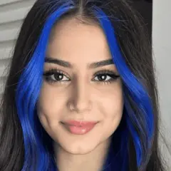 Chica con cabello oscuro y mechas money piece de color azul vibrante.