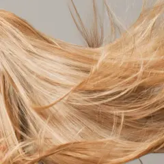 El sol aclara el pelo rubio de una mujer, moviéndose con el viento.