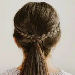 Dos trenzas laterales se unen en una coleta baja, un ejemplo de peinados sencillos y elegantes.