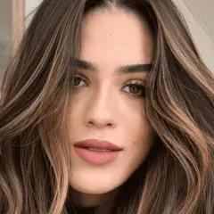 Mujer con cabello castaño oscuro y ondas suaves, resaltado por mechas shatush que aportan luz y dimensión.