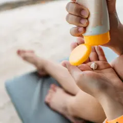 Manos aplicando crema solar en la palma. Recuerda que las cremas solares caducan y pierden efectividad.