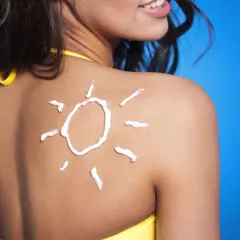 Crema solar en forma de sol sobre la espalda de una mujer, un consejo para como mantener el bronceado.