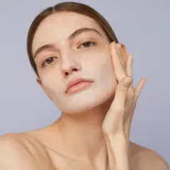Mujer aplicándose crema en el rostro, un paso clave para saber como exfoliar la piel y lograr un cutis radiante.