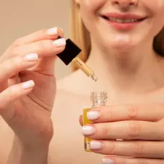 Manos aplicando un sérum con retinol y vitamina c.