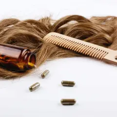 Cabello castaño, peine de madera y cápsulas. El zinc es bueno para el pelo, promoviendo su salud y crecimiento.