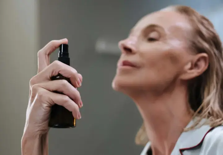 Mujer aplicando bruma facial para que sirve: refrescar e hidratar la piel.