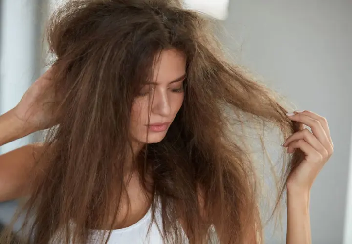 Mujer con pelo seco y enredado, buscando cómo hidratar el pelo para devolverle la vida y el brillo.