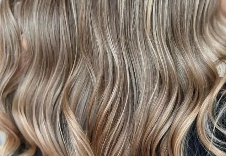 Cabello castaño con reflejos rubios sutiles, como baby lights, que le dan un toque natural y luminoso.