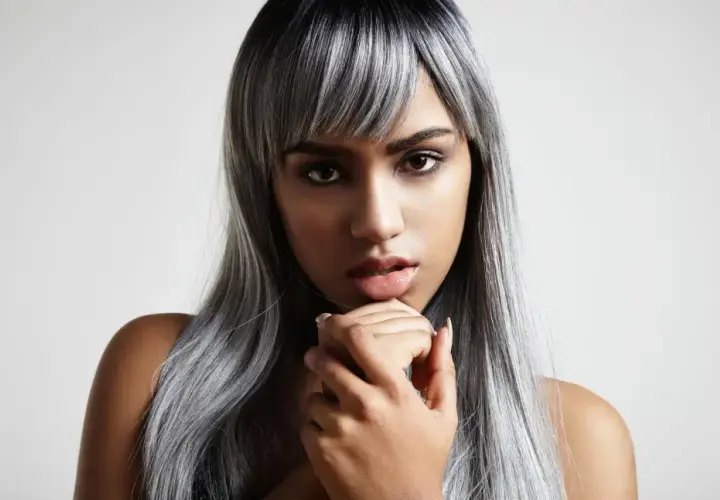 Mujer con cabello largo y liso, con mechas blancas que contrastan con su tono oscuro.
