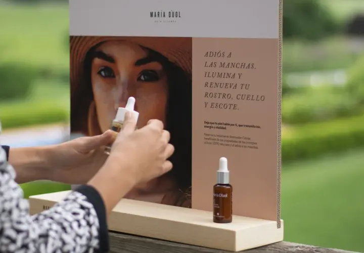 Manos sostienen un frasco de serum de vitamina C, ideal para combatir las manchas que la vitamina C mancha la piel con el sol.