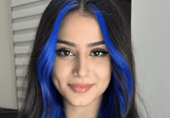 Chica con cabello oscuro y mechas money piece de color azul vibrante.