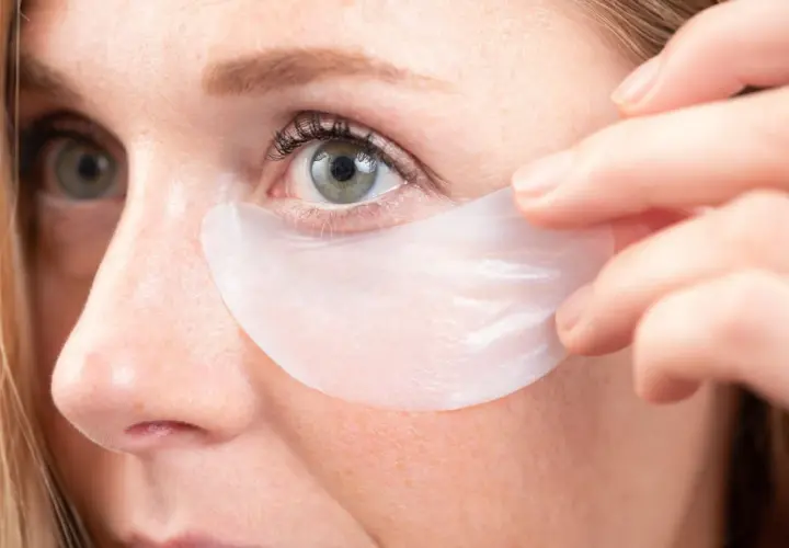 Aplicación de parches para el contorno de ojos. Una mujer se coloca un parche debajo del ojo para hidratar y revitalizar la piel.