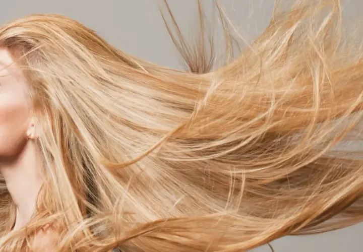 El sol aclara el pelo rubio de una mujer, moviéndose con el viento.