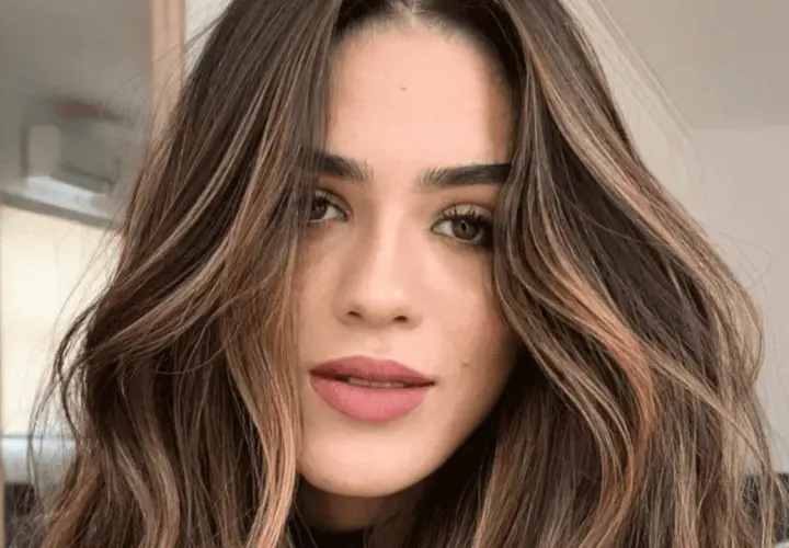 Mujer con cabello castaño oscuro y ondas suaves, resaltado por mechas shatush que aportan luz y dimensión.