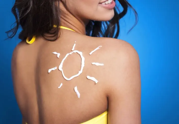 Crema solar en forma de sol sobre la espalda de una mujer, un consejo para como mantener el bronceado.