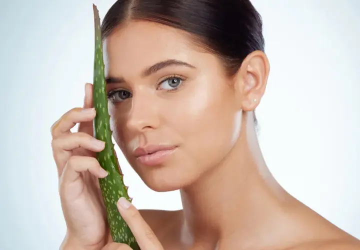 Mujer con hoja de aloe vera, mostrando cómo el aloe vera para que sirve para una piel radiante y saludable.
