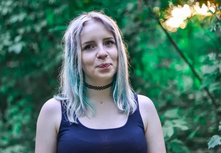 Chica con cabello teñido de azul y plateado, con piercing en la nariz. ¿Buscas como quitar el verde del pelo?