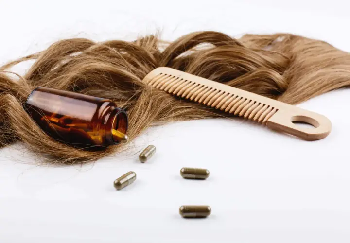 Cabello castaño, peine de madera y cápsulas. El zinc es bueno para el pelo, promoviendo su salud y crecimiento.