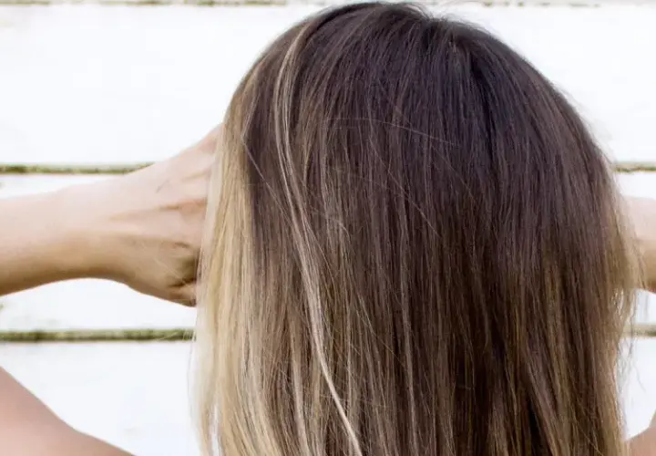 Cabello castaño con reflejos rubios, con las manos detrás de la cabeza.