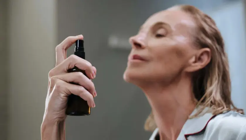 Mujer aplicando bruma facial para que sirve: refrescar e hidratar la piel.