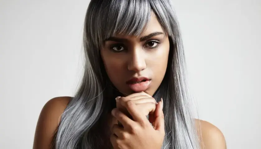 Mujer con cabello largo y liso, con mechas blancas que contrastan con su tono oscuro.