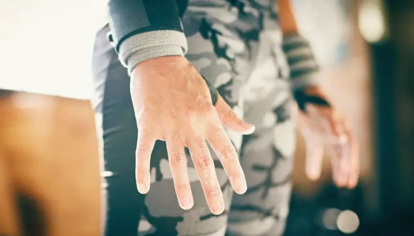 Manos con callos en los dedos, evidencia de entrenamiento duro. Muñequeras y pantalón de camuflaje completan la imagen.