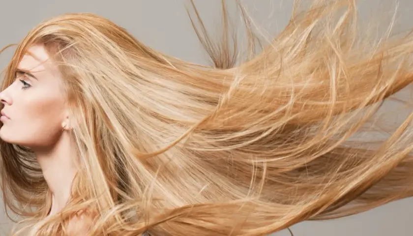 El sol aclara el pelo rubio de una mujer, moviéndose con el viento.