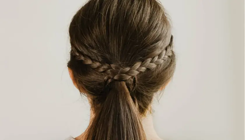 Dos trenzas laterales se unen en una coleta baja, un ejemplo de peinados sencillos y elegantes.