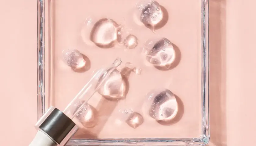 Gotas de sérum con glicerina para que sirve, humectando la piel. Pipeta de cristal sobre fondo rosa.