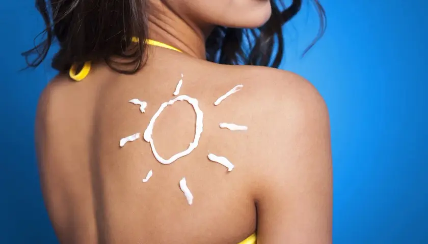 Crema solar en forma de sol sobre la espalda de una mujer, un consejo para como mantener el bronceado.
