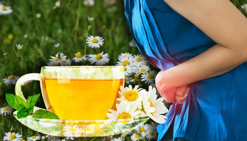 Té de manzanilla con menta, rodeado de flores. Una persona con dolor abdominal se alivia con los beneficios de la manzanilla.