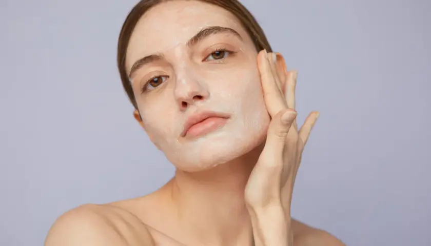 Mujer aplicándose crema en el rostro, un paso clave para saber como exfoliar la piel y lograr un cutis radiante.