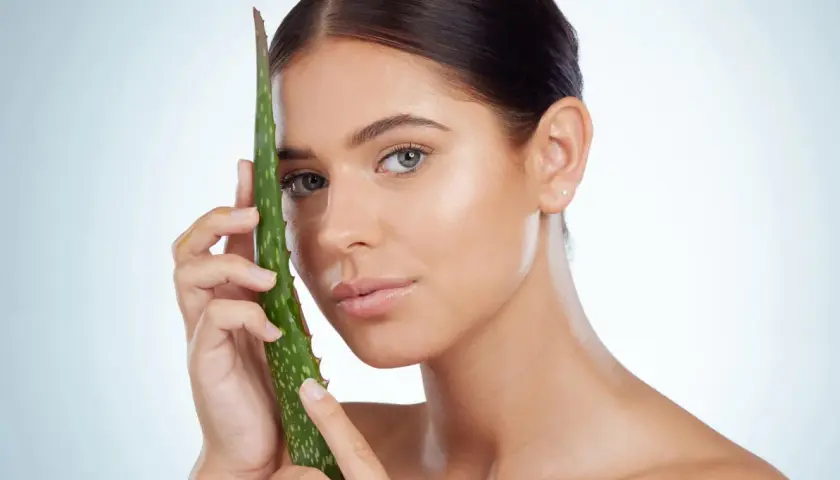 Mujer con hoja de aloe vera, mostrando cómo el aloe vera para que sirve para una piel radiante y saludable.