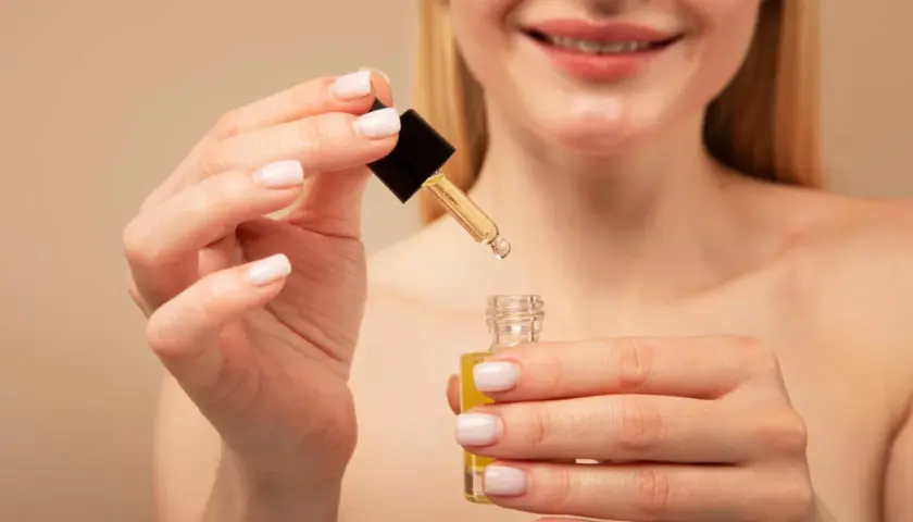 Manos aplicando un sérum con retinol y vitamina c.