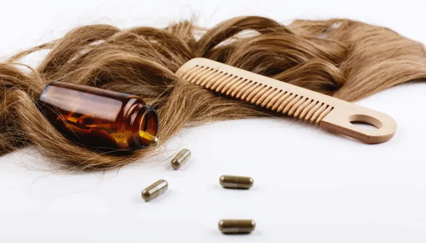 Cabello castaño, peine de madera y cápsulas. El zinc es bueno para el pelo, promoviendo su salud y crecimiento.