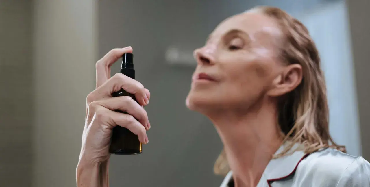 Mujer aplicando bruma facial para que sirve: refrescar e hidratar la piel.