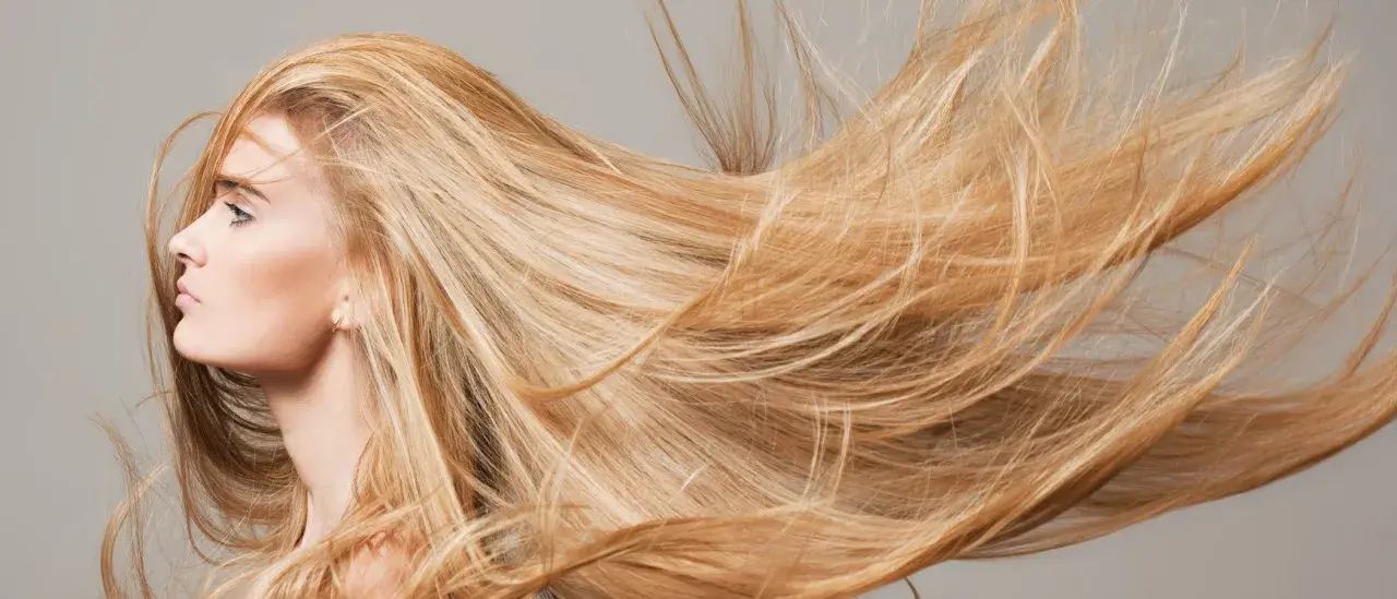 El sol aclara el pelo rubio de una mujer, moviéndose con el viento.