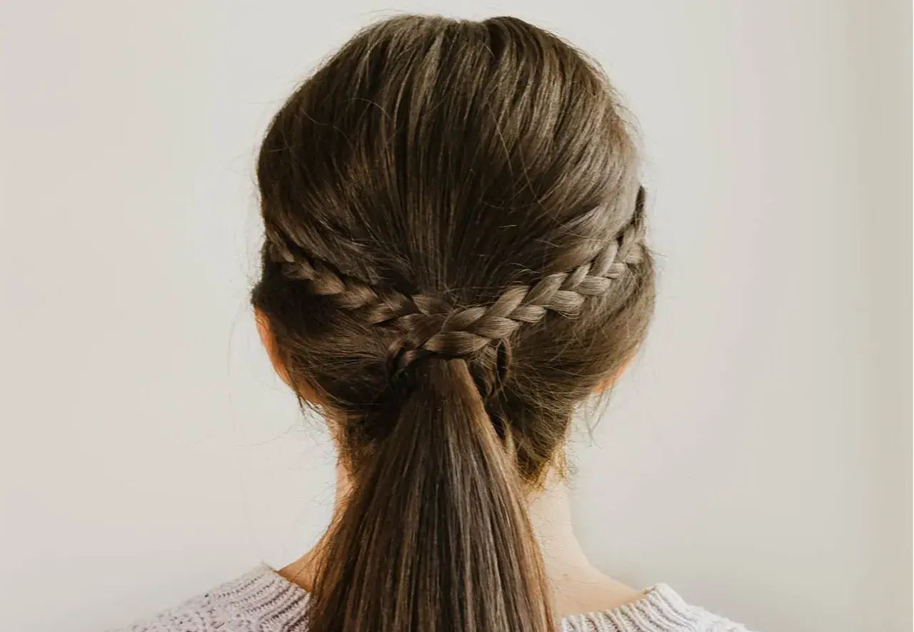 Dos trenzas laterales se unen en una coleta baja, un ejemplo de peinados sencillos y elegantes.
