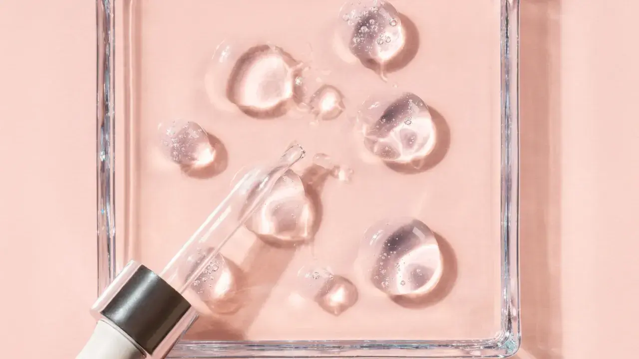 Gotas de sérum con glicerina para que sirve, humectando la piel. Pipeta de cristal sobre fondo rosa.