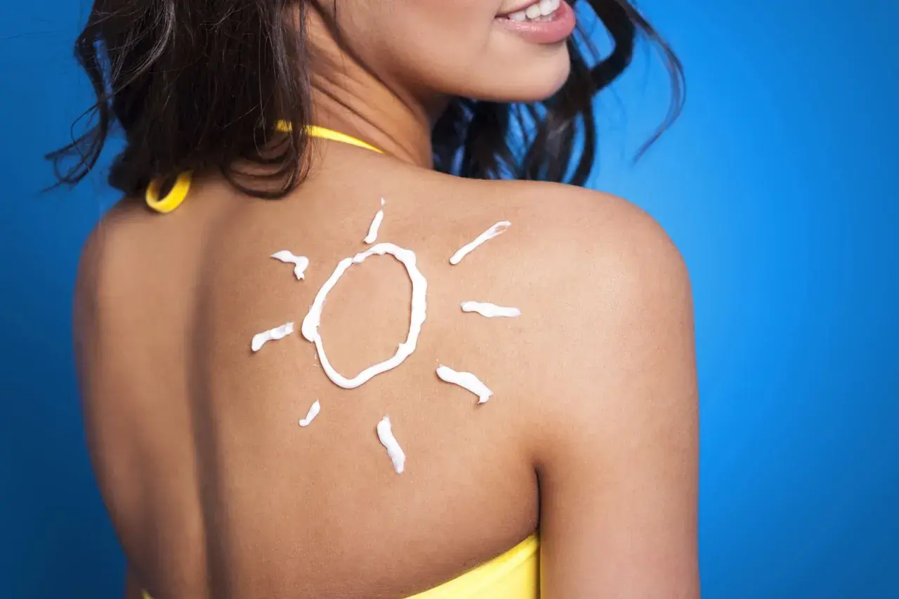 Crema solar en forma de sol sobre la espalda de una mujer, un consejo para como mantener el bronceado.