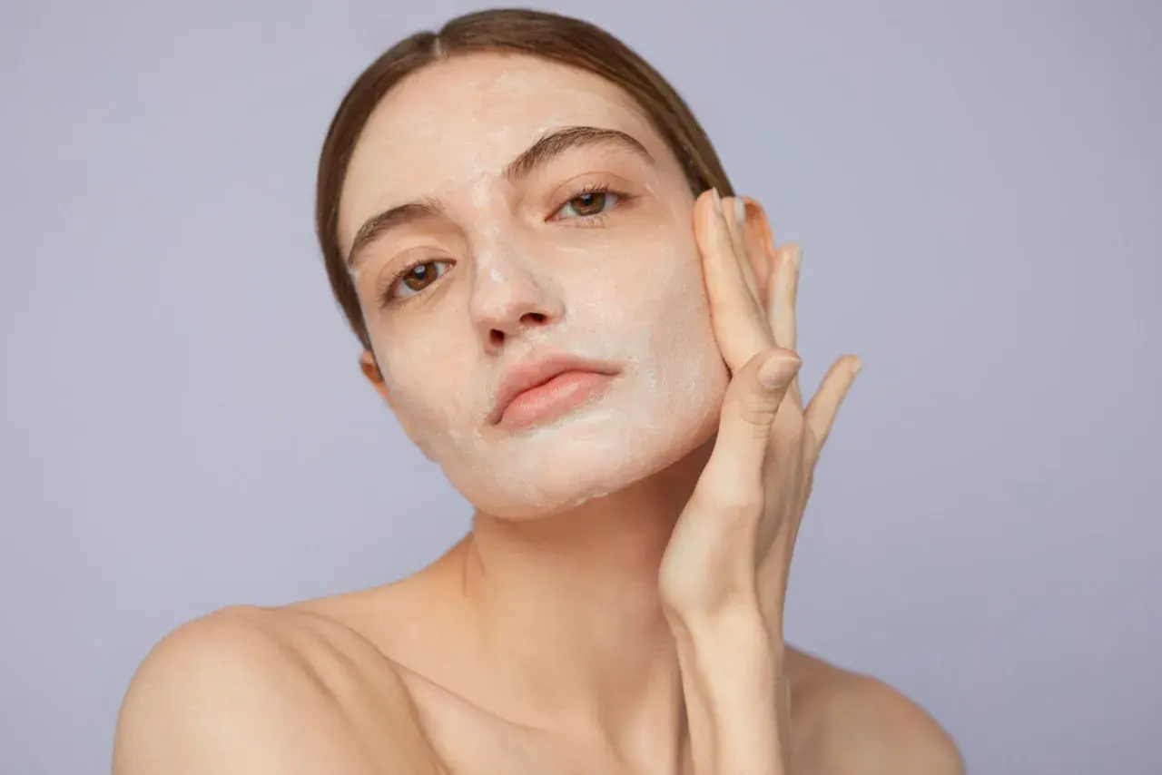 Mujer aplicándose crema en el rostro, un paso clave para saber como exfoliar la piel y lograr un cutis radiante.