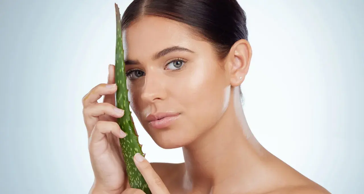 Mujer con hoja de aloe vera, mostrando cómo el aloe vera para que sirve para una piel radiante y saludable.