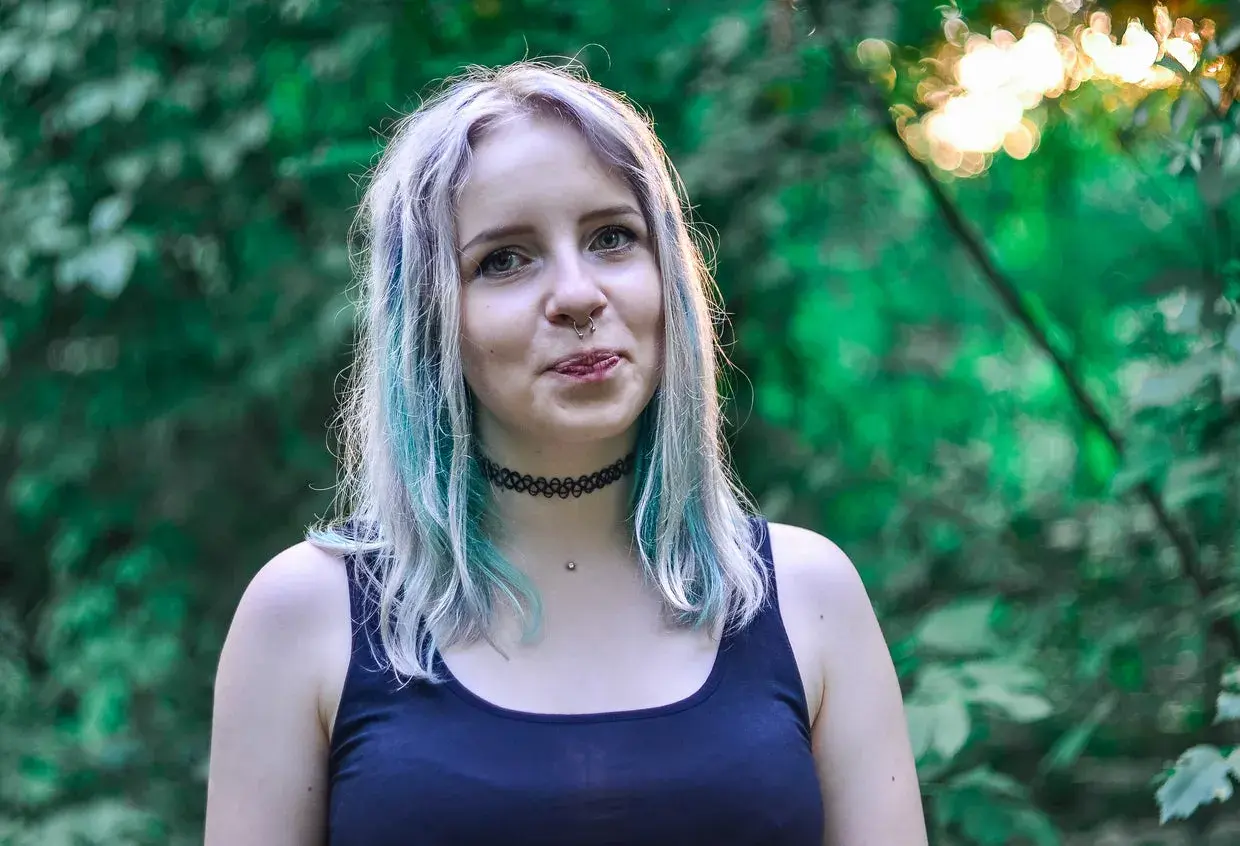 Chica con cabello teñido de azul y plateado, con piercing en la nariz. ¿Buscas como quitar el verde del pelo?