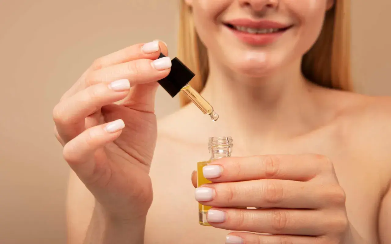 Manos aplicando un sérum con retinol y vitamina c.